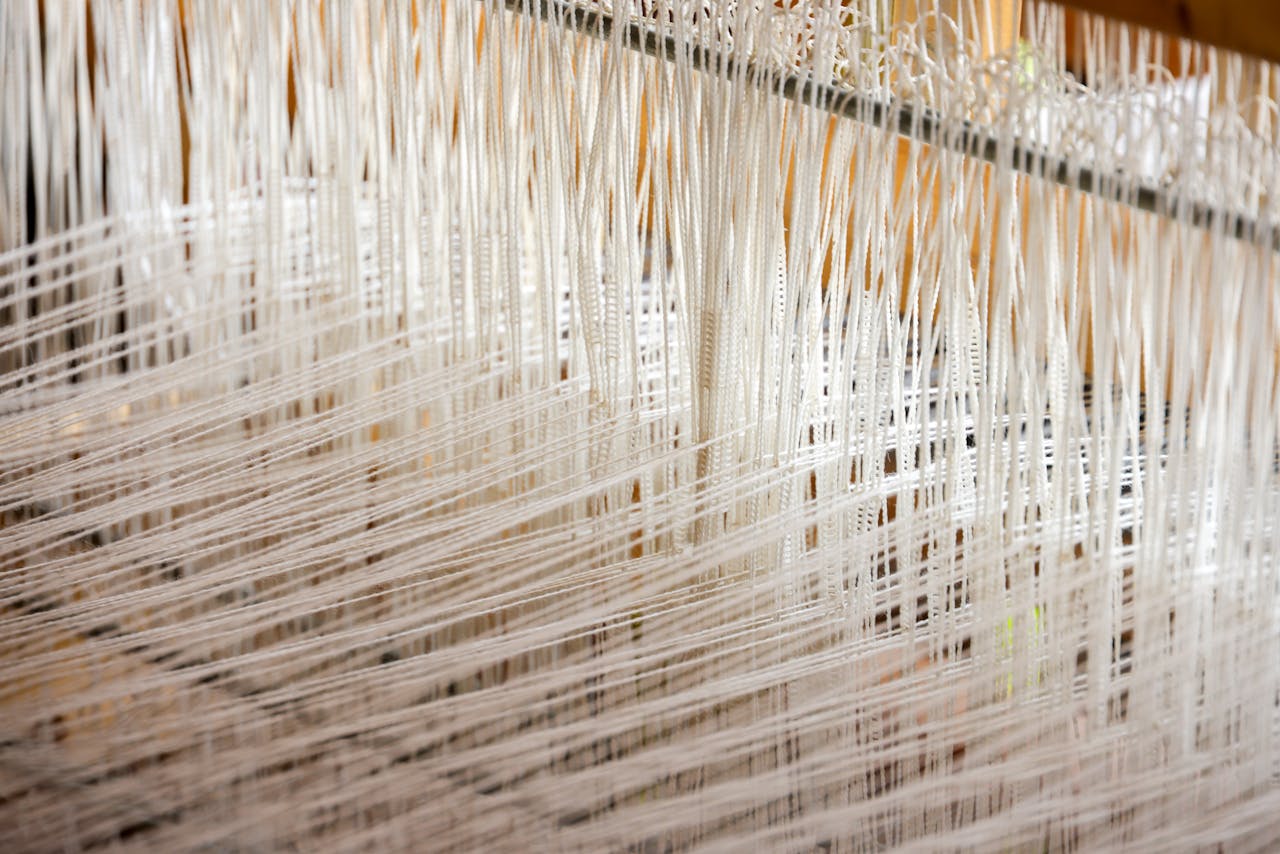 Detailed view of white threads woven on a loom, showcasing intricate textile work.