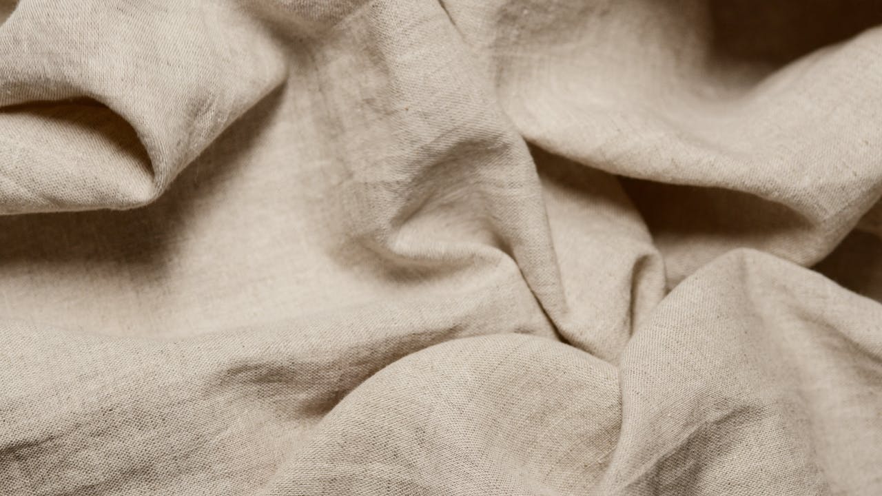 Close-up of beige cotton fabric showcasing natural texture and crumples.