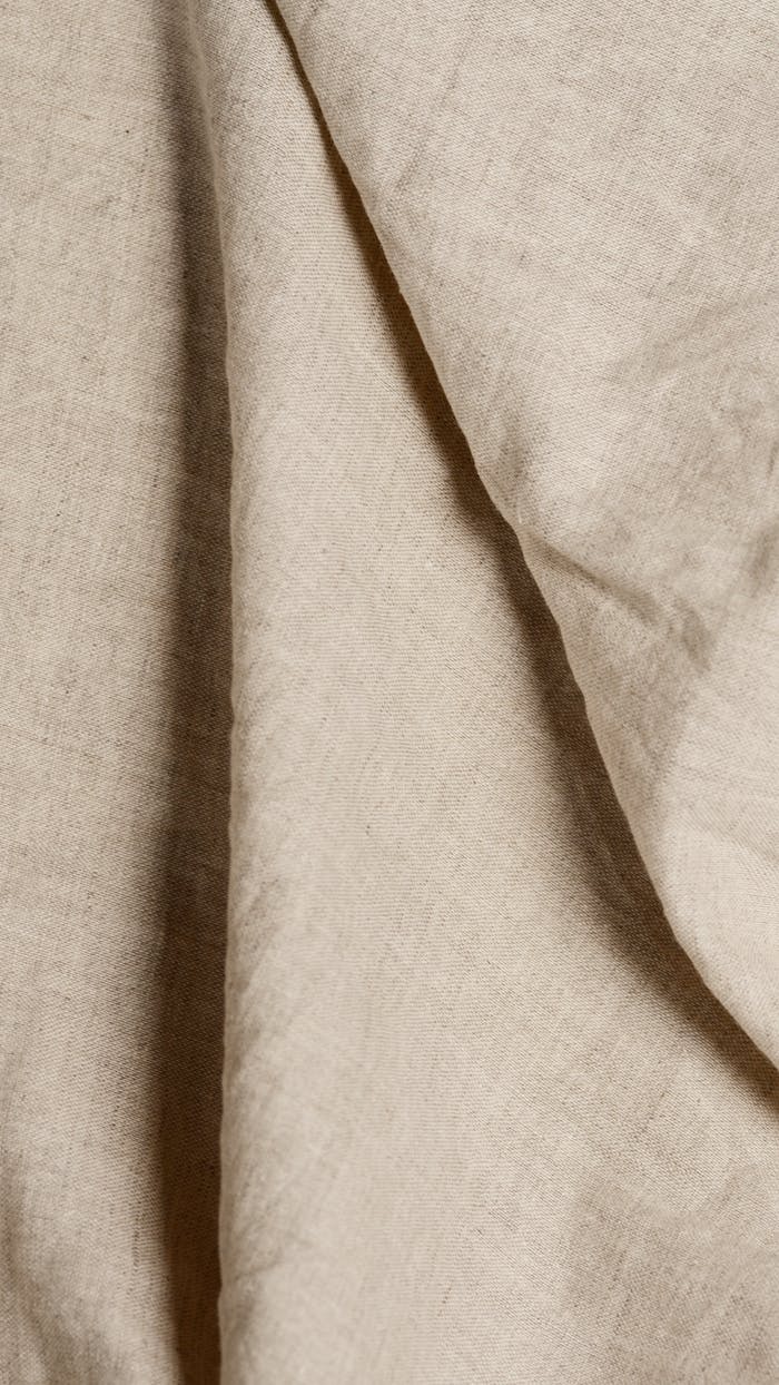 Detailed view of beige fabric with soft folds creating texture and pattern.